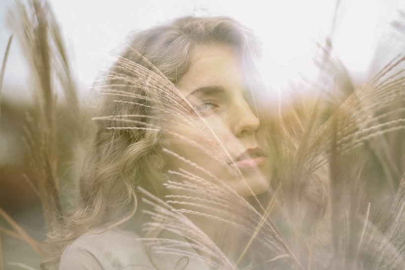 a woman looking out of a field of wheat